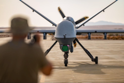 A Crew Chief assigned to the 163d Attack Wing, March Air Reserve Base marshals MQ-9 Reaper on the Strategic Expeditionary Landing Field on Marine Corps Air Ground Combat Center Twentynine Palms, CA July 21, 2022. The 163d accelerated change by pioneering the first ever refueling of the MQ-9 Reaper using a Forward Area refueling Point provided by the VMM - 764’s V-22 Osprey. (U.S. Air National Guard photo by Staff Sgt. Joseph Pagan)