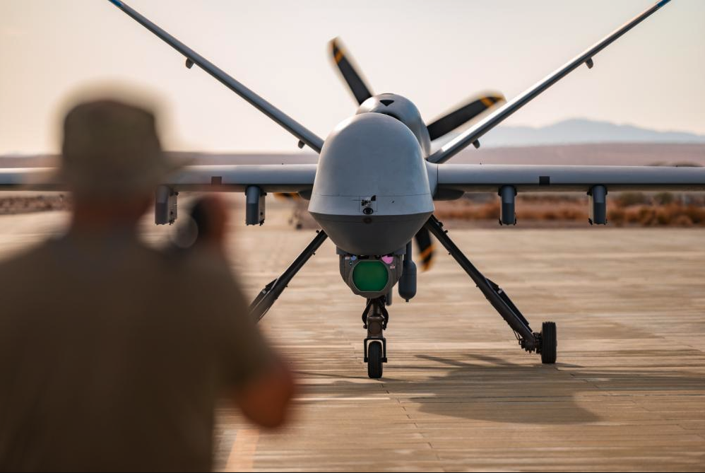 A Crew Chief assigned to the 163d Attack Wing, March Air Reserve Base marshals MQ-9 Reaper on the Strategic Expeditionary Landing Field on Marine Corps Air Ground Combat Center Twentynine Palms, CA July 21, 2022. The 163d accelerated change by pioneering the first ever refueling of the MQ-9 Reaper using a Forward Area refueling Point provided by the VMM - 764’s V-22 Osprey. (U.S. Air National Guard photo by Staff Sgt. Joseph Pagan)